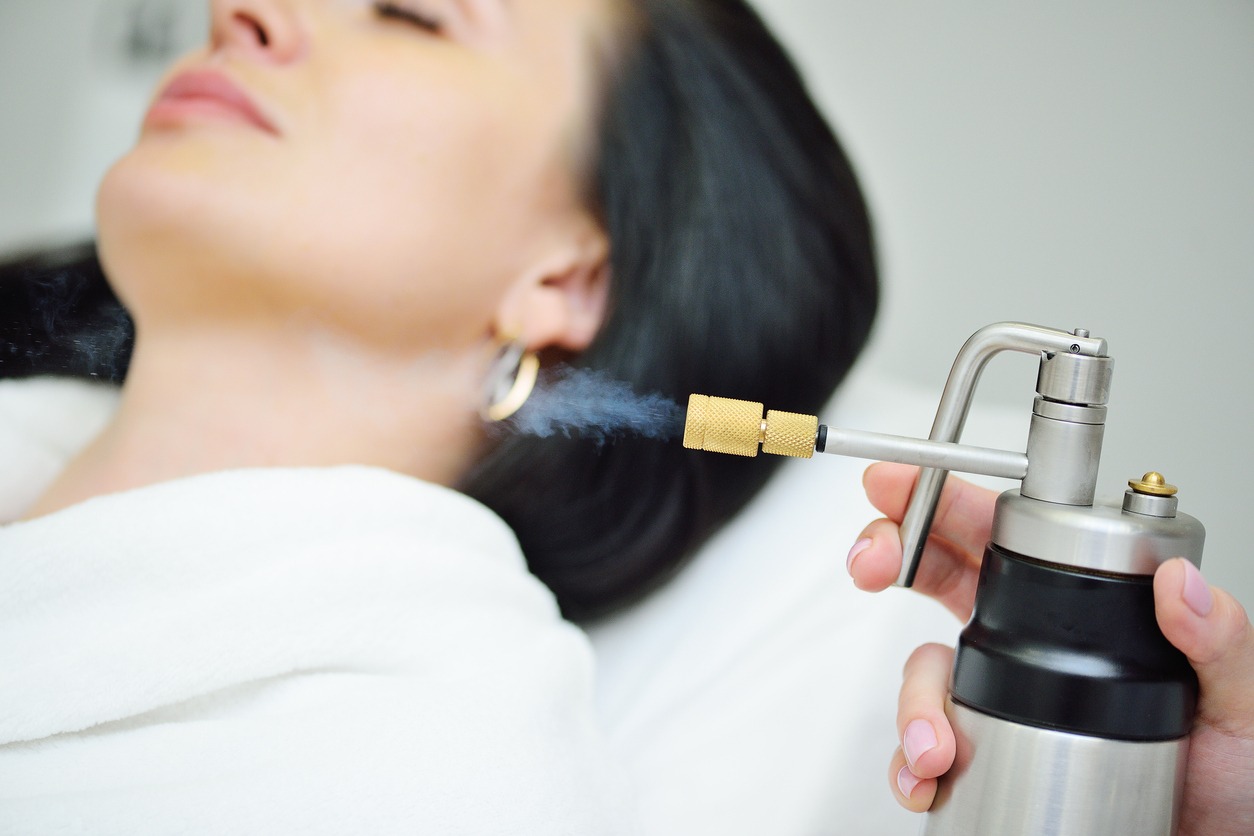 cosmetologist makes a cryomassage of the face to the patient – a cosmetological procedure of exposure to the skin with liquefied nitrogen using a cryodestructor apparatus