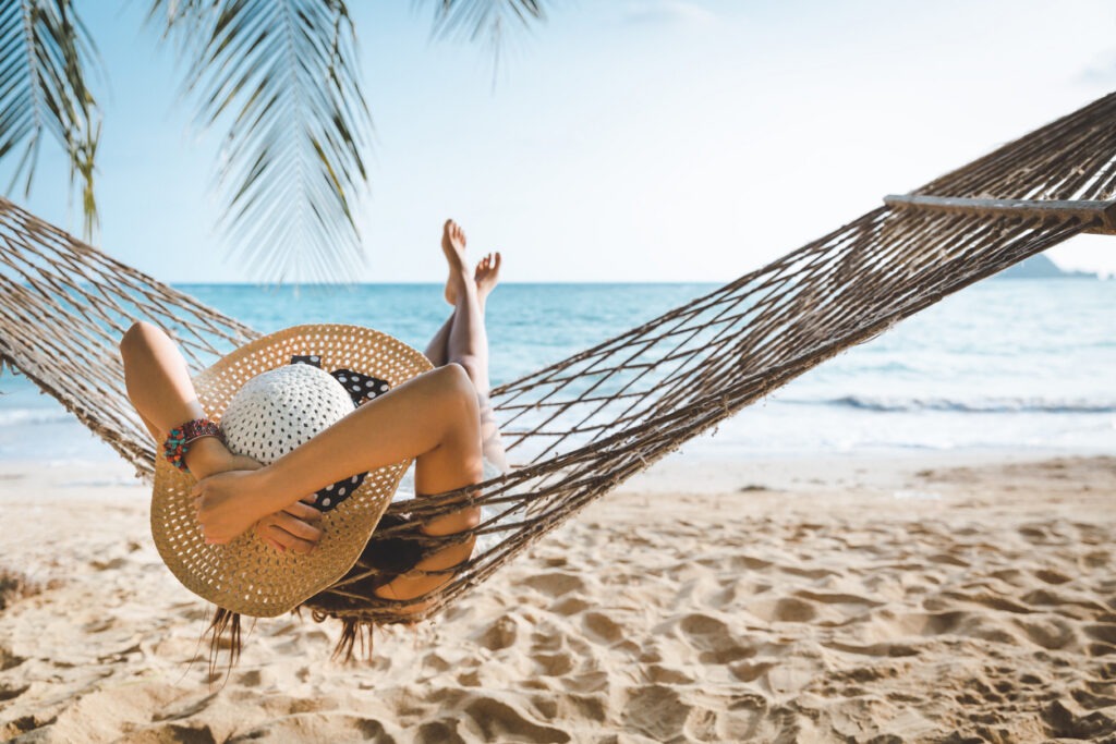 Traveler enjoying summer Hollidays at the beach while wearing a hat and clothes as sun barriers.